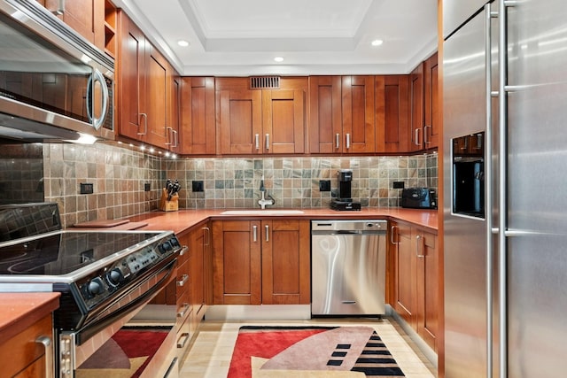 kitchen featuring a sink, a raised ceiling, stainless steel appliances, and recessed lighting
