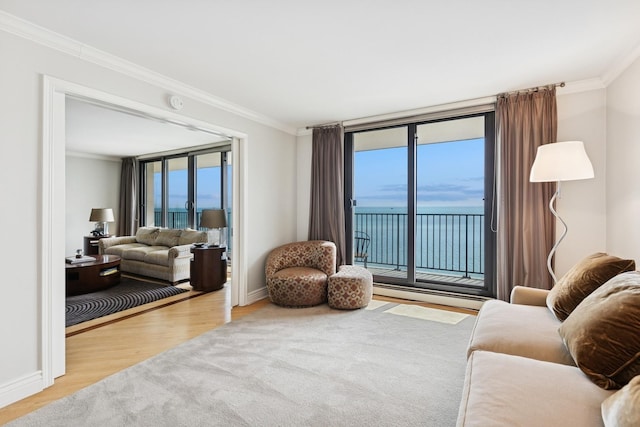 living room featuring a water view, baseboards, ornamental molding, and wood finished floors