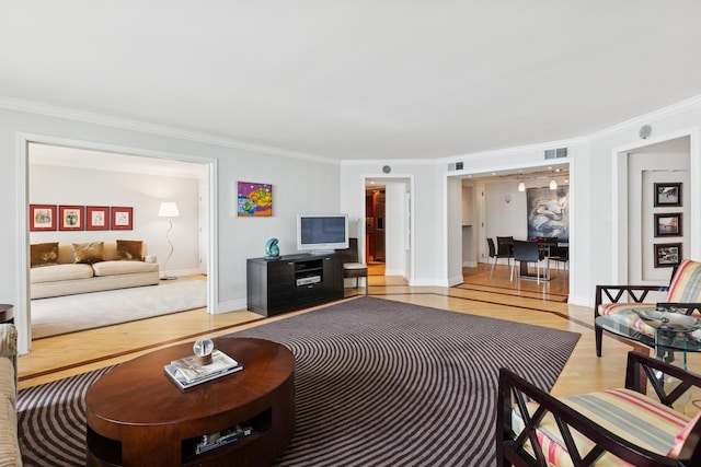 living area featuring visible vents, ornamental molding, baseboards, and wood finished floors