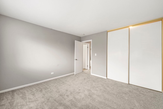 unfurnished bedroom with a closet, baseboards, and light carpet