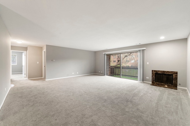 unfurnished living room with carpet floors, baseboards, and plenty of natural light