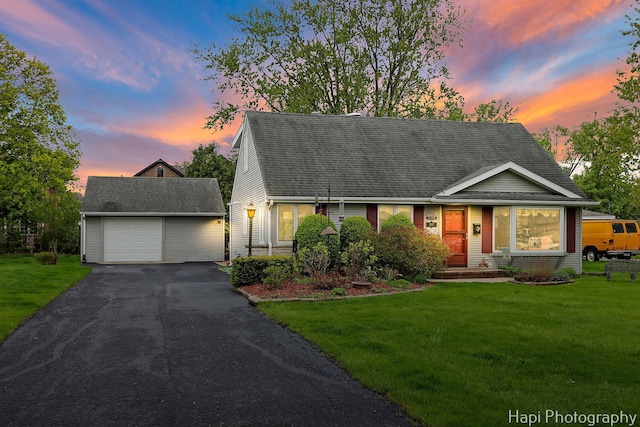 cape cod home with an outdoor structure, a yard, driveway, and a garage