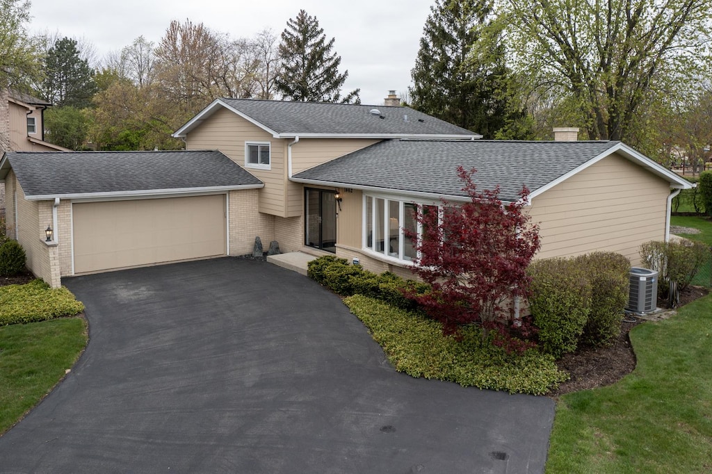 1462 Hemlock Knoll Ter, Northbrook, IL 60062 - view of front of house with brick siding, a garage, a chimney, driveway, and central AC
