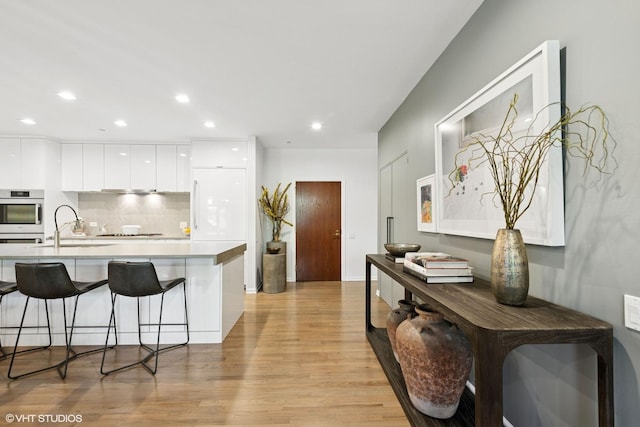 33 W Huron St Unit 309, Chicago, IL 60654 - kitchen with modern cabinets, light wood-style floors, a breakfast bar, white cabinets, and a sink