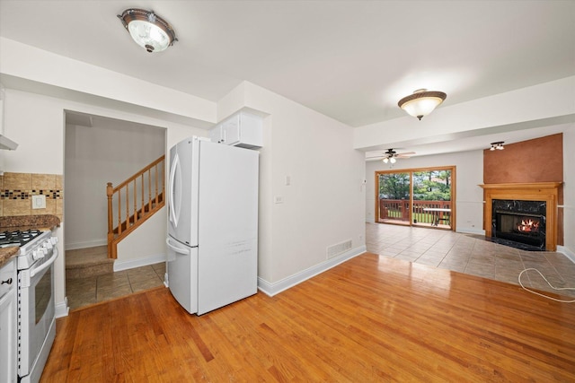 interior space with light wood finished floors, a premium fireplace, visible vents, white cabinetry, and white appliances