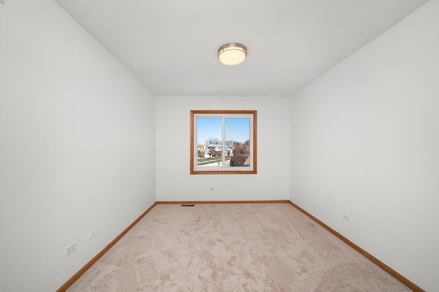 carpeted spare room with visible vents and baseboards