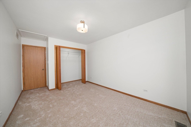 unfurnished bedroom with a closet, visible vents, light carpet, and baseboards