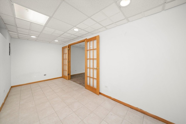 empty room with recessed lighting, a paneled ceiling, french doors, and baseboards