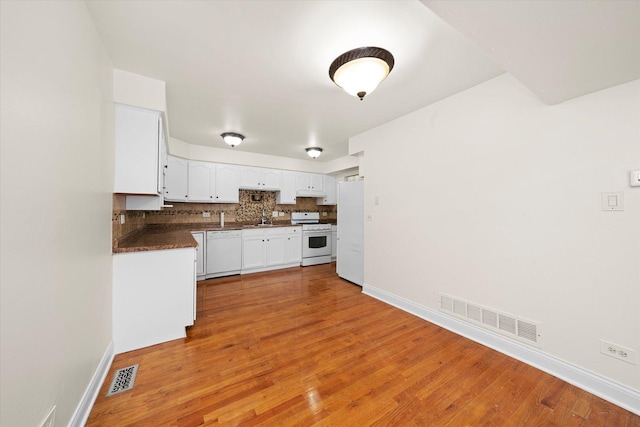 kitchen with a sink, dark countertops, visible vents, and white appliances