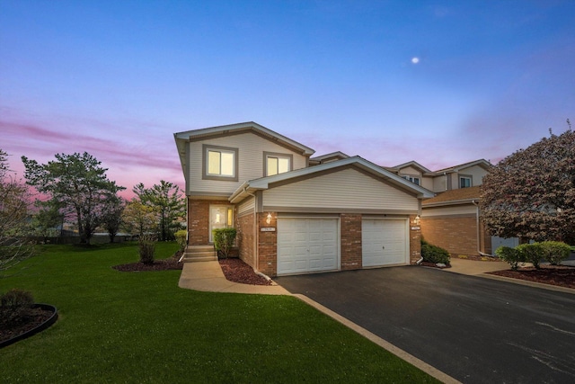 traditional-style house featuring a front lawn, aphalt driveway, brick siding, and a garage