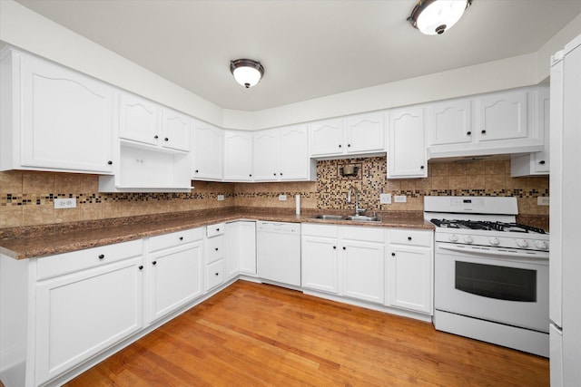 kitchen with a sink, under cabinet range hood, white appliances, dark countertops, and white cabinets