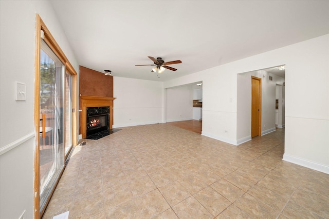 unfurnished living room with baseboards, a ceiling fan, and a premium fireplace