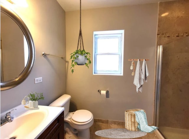 full bathroom featuring toilet, vanity, tile patterned flooring, and a stall shower
