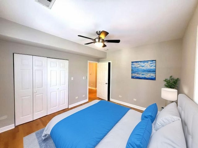 bedroom with a closet, wood finished floors, visible vents, and baseboards