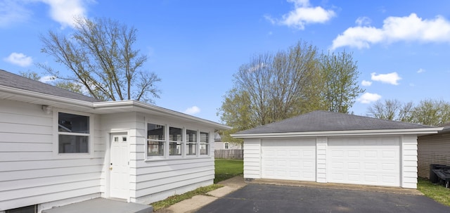 view of side of home featuring a detached garage, an outbuilding, and a shingled roof