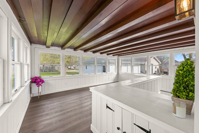 unfurnished sunroom with a decorative wall, wood finished floors, wooden ceiling, and beamed ceiling