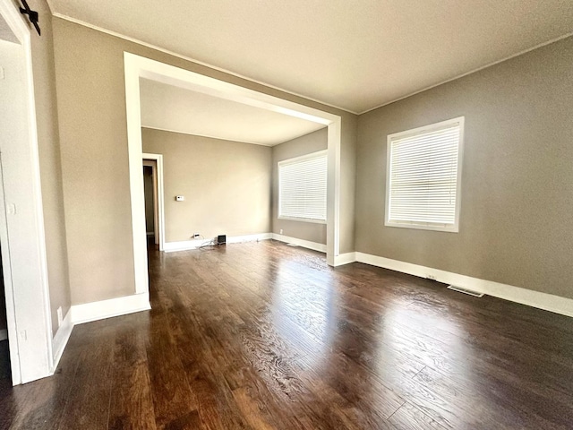 spare room featuring visible vents, baseboards, and wood finished floors