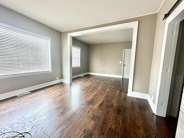 empty room featuring baseboards, wood finished floors, and visible vents