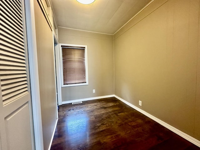 unfurnished bedroom featuring dark wood finished floors, crown molding, and baseboards
