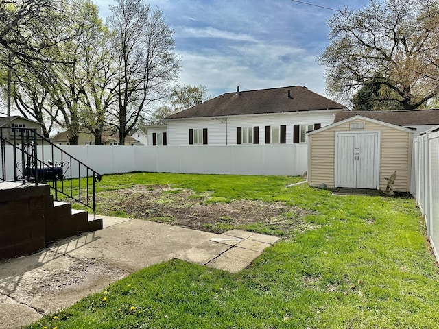 view of yard with a fenced backyard, stairway, an outbuilding, and a storage unit