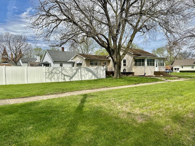 exterior space featuring a front lawn, fence, and a sunroom