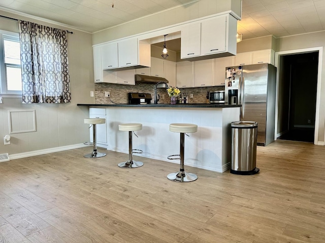kitchen with a peninsula, dark countertops, appliances with stainless steel finishes, and white cabinetry