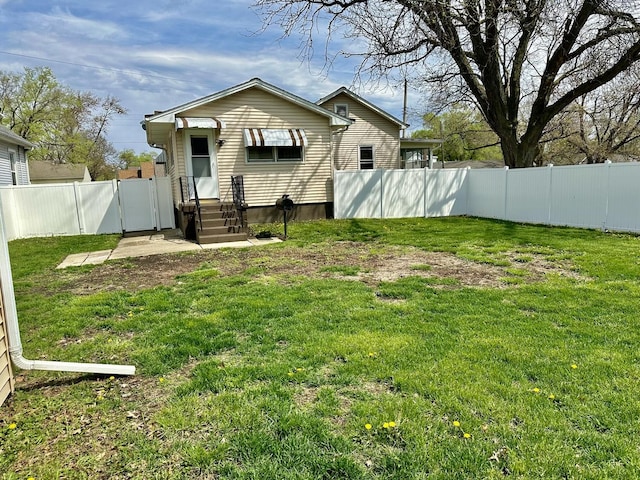 rear view of house featuring a fenced backyard, a gate, and a yard
