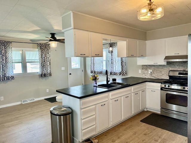 kitchen with under cabinet range hood, visible vents, a sink, stainless steel range with gas cooktop, and a peninsula