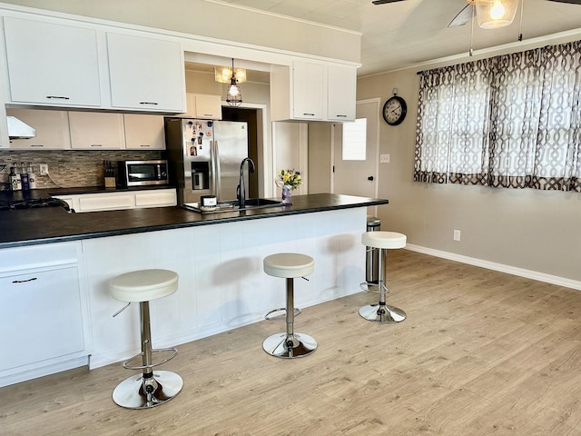 kitchen featuring dark countertops, a peninsula, appliances with stainless steel finishes, and light wood finished floors