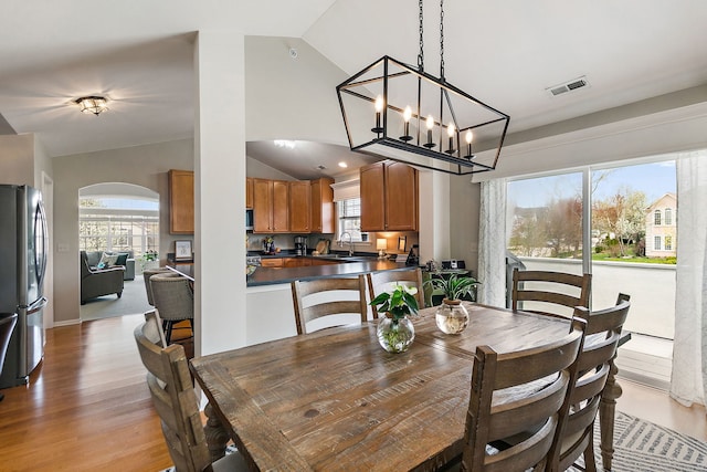 dining area featuring a healthy amount of sunlight, visible vents, light wood finished floors, and lofted ceiling