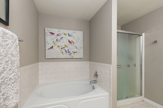 bathroom featuring tile patterned flooring, a bath, and a stall shower