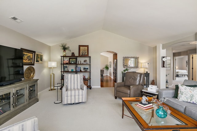 carpeted living room with arched walkways, baseboards, visible vents, and lofted ceiling