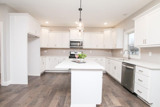 kitchen with white cabinets, a center island, stainless steel appliances, and a sink
