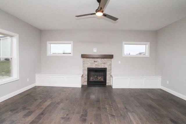 unfurnished living room featuring a wealth of natural light, a fireplace, ceiling fan, and dark wood-style flooring