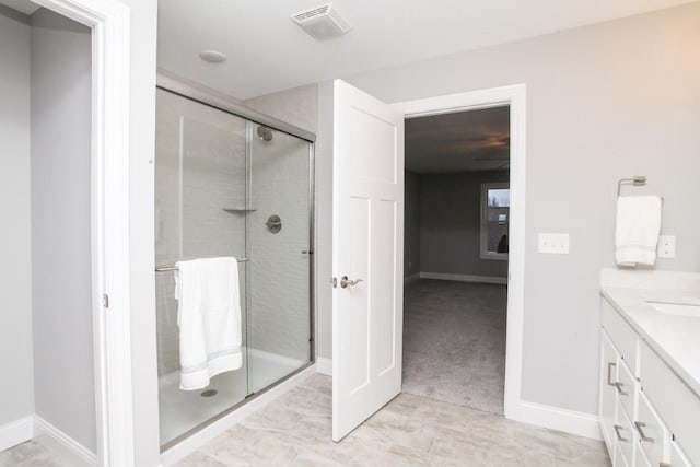 bathroom featuring visible vents, baseboards, vanity, and a stall shower