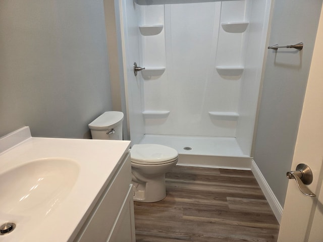 bathroom featuring walk in shower, wood finished floors, vanity, and toilet