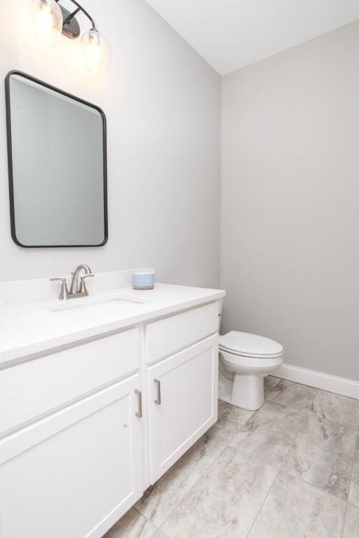 bathroom with marble finish floor, toilet, and vanity