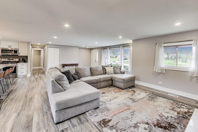 living area with recessed lighting, light wood-type flooring, visible vents, and baseboards