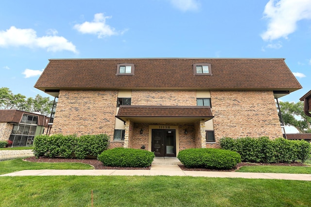 11138 Center Rd Unit E22, Palos Hills, IL 60465 - view of front facade with brick siding, mansard roof, a front lawn, and roof with shingles
