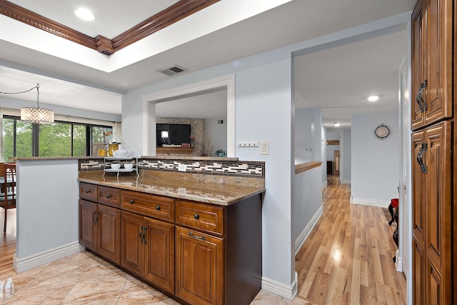 11138 Center Rd Unit E22, Palos Hills, IL 60465 - kitchen featuring light stone countertops, tasteful backsplash, brown cabinets, decorative light fixtures, and light wood finished floors