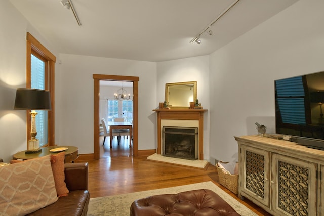 1726 Wesley Ave, Evanston, IL 60201 - living room featuring baseboards, a chandelier, a fireplace with raised hearth, wood finished floors, and track lighting