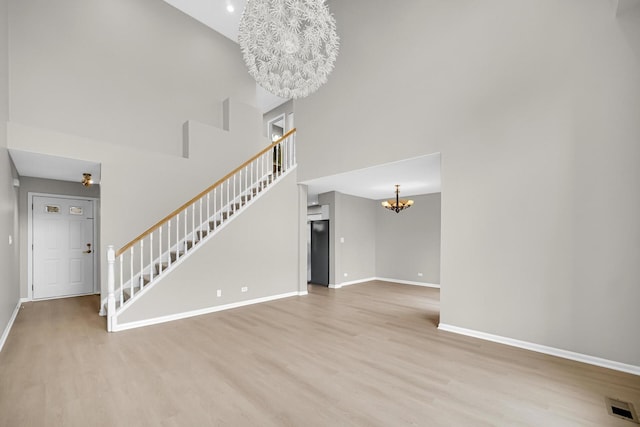 2073 Cambria Ct, Northbrook, IL 60062 - unfurnished living room with stairs, an inviting chandelier, light wood-style flooring, baseboards, and visible vents