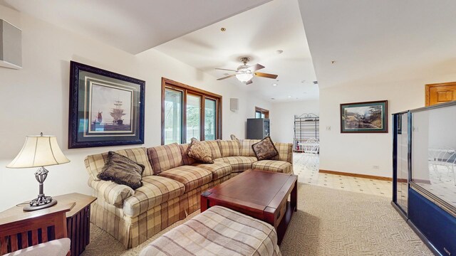 living room featuring light colored carpet, a ceiling fan, and baseboards