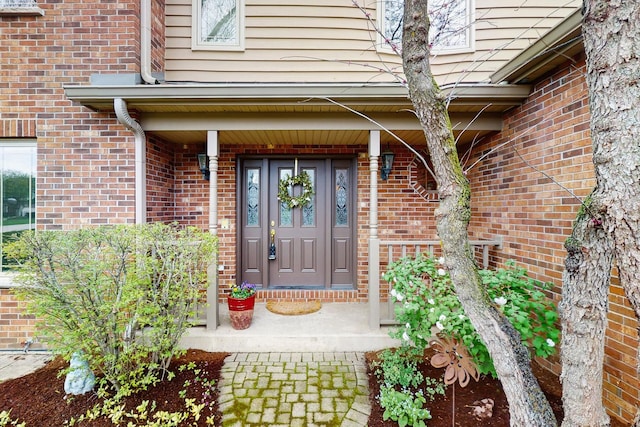 property entrance featuring a porch and brick siding