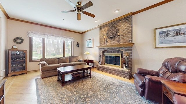 living room featuring ceiling fan, crown molding, a fireplace, wood finished floors, and baseboards