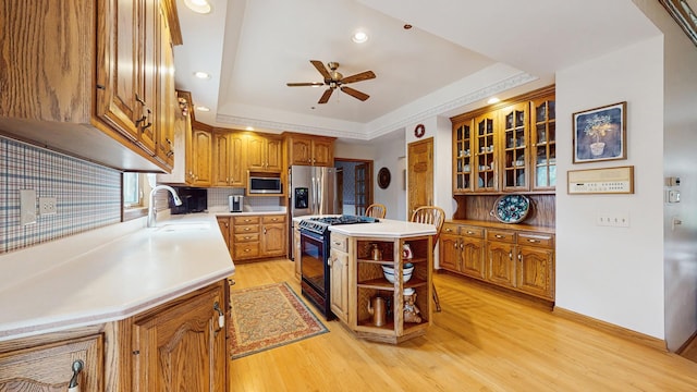 kitchen featuring ceiling fan, a sink, stainless steel appliances, light wood-type flooring, and backsplash