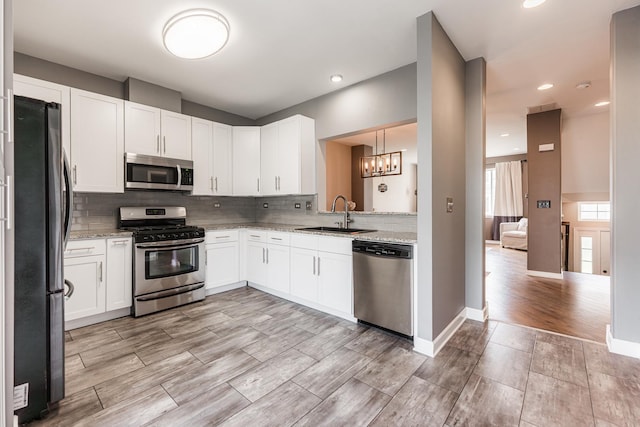1106 Andover Ct, Glendale Heights, IL 60139 - kitchen featuring appliances with stainless steel finishes, a sink, a chandelier, tasteful backsplash, and light stone counters