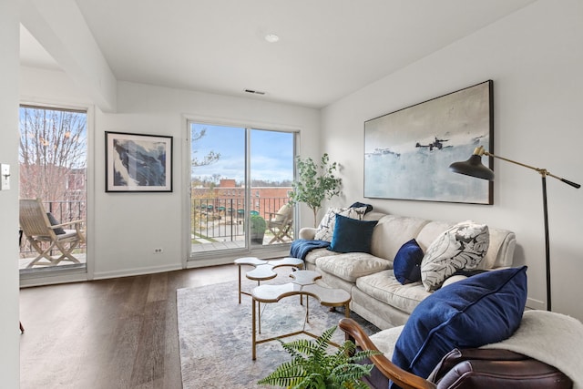 living room featuring visible vents, baseboards, and wood finished floors
