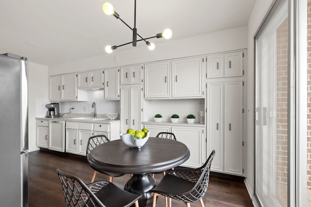 kitchen featuring dark wood-style floors, light countertops, a sink, freestanding refrigerator, and white cabinetry
