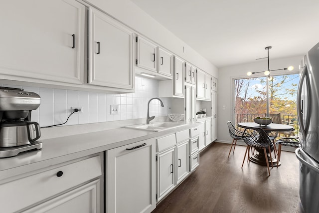 kitchen featuring light countertops, freestanding refrigerator, a sink, and backsplash